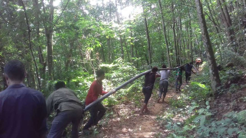 Orang Asli villagers and volunteers carrying piping through the jungle