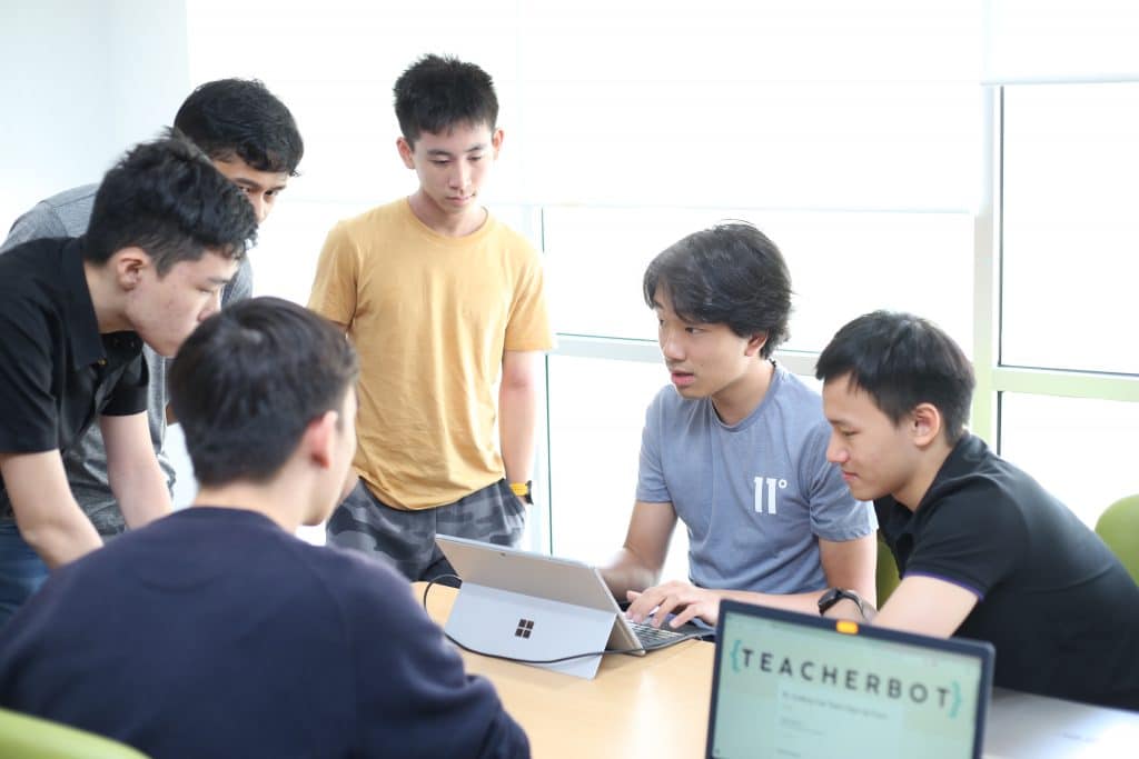 A group of students brainstorming around laptops