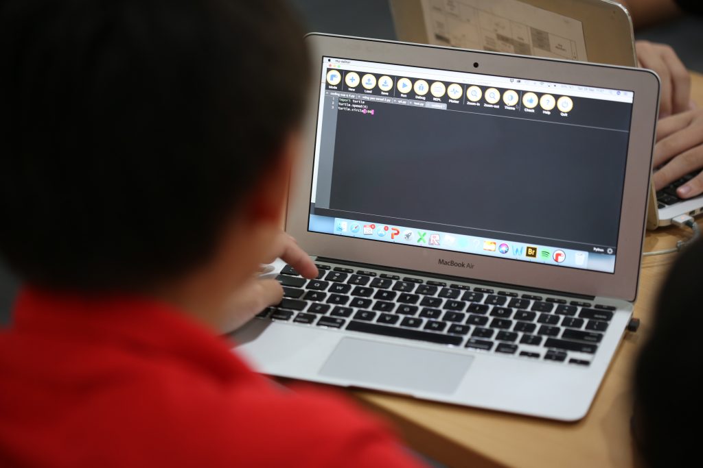 Over the shoulder shot of a student coding on his laptop