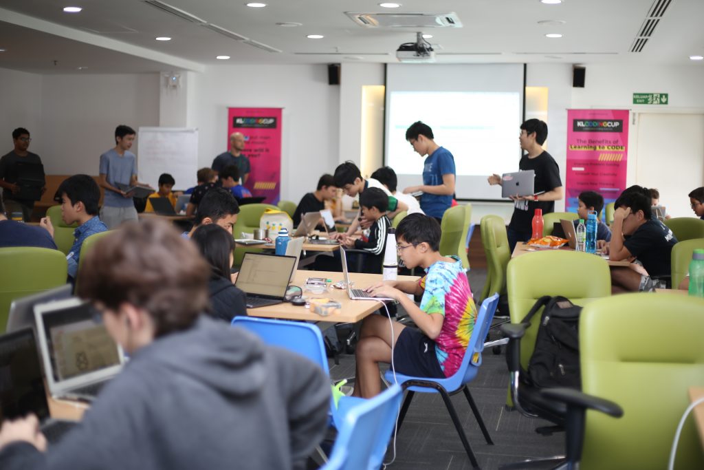 School kids coding on their laptops in a presentation hall