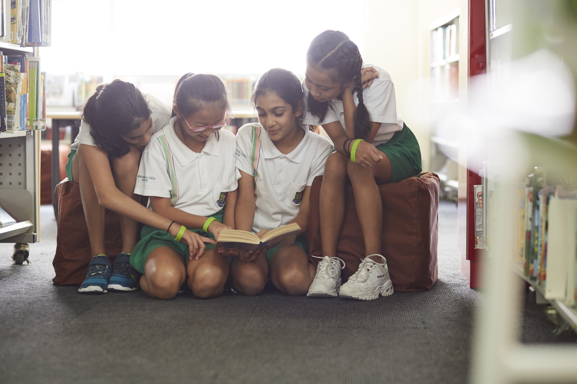 four school girls reading in library